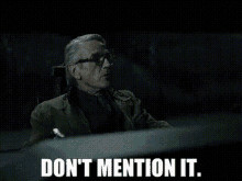 a man in a suit and tie is sitting at a table and says do n't mention it