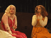 a woman in a red dress is sitting next to another woman