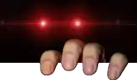 a person 's fingers are sticking out of a hole in the dark with red lights behind them