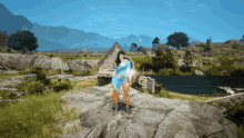 a woman in a blue dress is standing on a rock near a lake