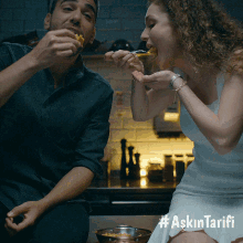 a man and a woman are sitting at a table eating food with the hashtag askin tarifi