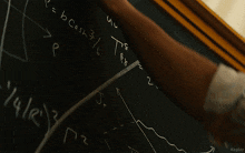 a man stands in front of a blackboard with a few numbers on it