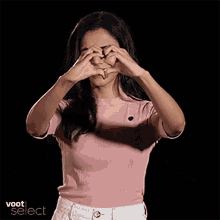 a woman making a heart shape with her hands in front of a black background with voot select written on it