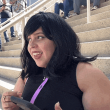 a woman wearing a black tank top with a purple lanyard around her neck that says ' sdg ' on it