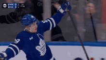 a toronto maple leafs hockey player holds his stick up in the air