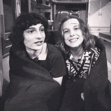 a boy and a girl are wrapped in a blanket and smiling for the camera