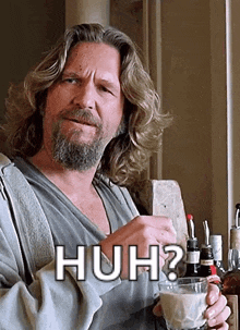 a man with long hair and a beard is holding a cup of coffee and says huh