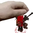a hand is holding a red nutcracker toy with a gun .