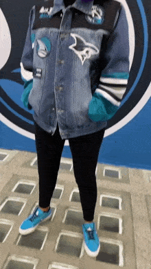 a woman wearing a sharks jacket and blue sneakers