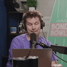a man wearing headphones is sitting in front of a microphone in front of a sign that says " bond bowls "