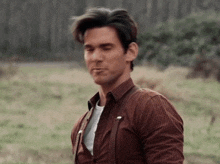 a man in a plaid shirt is standing in a field with his eyes closed .