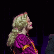 a woman wearing a purple dress and a green wig is smiling