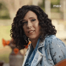 a woman with curly hair is wearing a denim jacket and a denim shirt .
