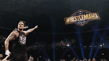 a wrestler is standing in front of a sign that says wrestlemania