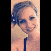 a woman is smiling and touching her hair .