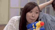 a woman is holding a water gun and making a face