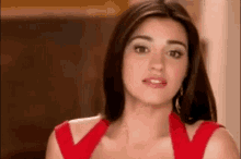 a woman in a red dress is looking at the camera and making a funny face .