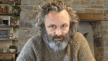 a man with curly hair and a beard is wearing a sweater with the hashtag @itsscottiesstark on the bottom