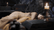 a woman is laying on a bed with a candle in front of her