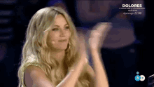 a woman applauds in front of a microphone on a television screen that says dolores on it