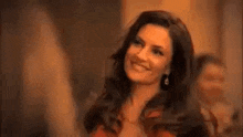 a woman in a red dress is smiling and waving at the camera .