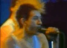 a blurry picture of a man singing into a microphone with a blue background