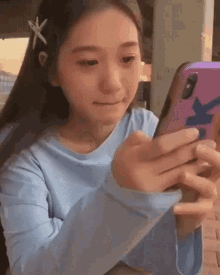 a girl with a starfish in her hair is looking at her cell phone