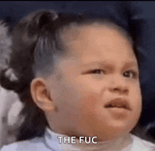 a little girl is making a funny face with the words `` the fuc '' written on her face .