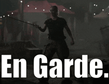 a man in a black shirt is holding a stick in front of the words en garde