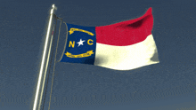 a nc flag is flying in the wind against a blue sky