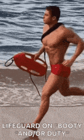 a shirtless lifeguard is running on the beach with a life preserver .