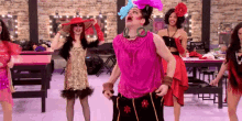 a man in a pink dress is dancing with a group of women .