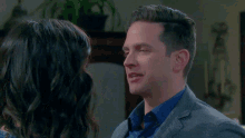 a man in a suit and a woman in a blue shirt are hugging each other