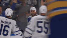 a hockey player with the number 55 on his jersey stands next to another player
