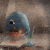 a blue toy dolphin is sitting on a table eating a sandwich .
