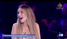 a woman is laughing in front of a microphone on a television show .