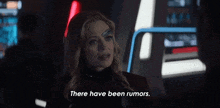 a woman with a robotic eye on her face is standing in a dark room and saying `` there have been rumors . ''
