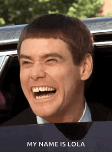 a man is laughing while sitting in a car with the words " my name is lola " below him