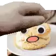 a person is holding a cookie on a plate with a face on it .