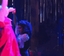a woman in a pink dress is dancing with another woman in a white wig