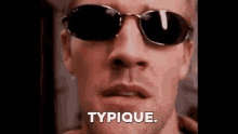 a close up of a man wearing sunglasses and saying typique .