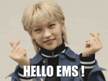 a girl with blonde hair is making a heart shape with her hands and the words hello ems below her