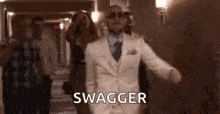 a man in a suit and tie is dancing in a hallway with a group of people behind him .
