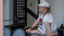 a man is sitting on a bench in a gym holding a pair of dumbbells .