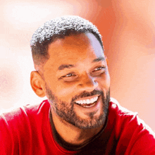 a man with a beard wearing a red shirt smiles