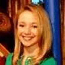 a close up of a woman 's face with blonde hair and a green shirt .
