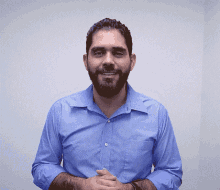 a man with a beard wearing a blue shirt is smiling