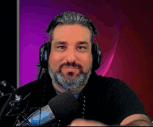 a man with a beard wears headphones and a microphone