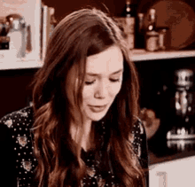 a woman with long brown hair is crying while sitting in front of a laptop computer .
