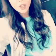 a woman wearing a white jacket and a blue shirt takes a selfie
